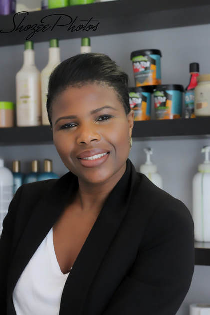 The owner of Marieme D Hair smiling and looking into the camera. She is wearing a white t-shirt and a smart black jacket.
