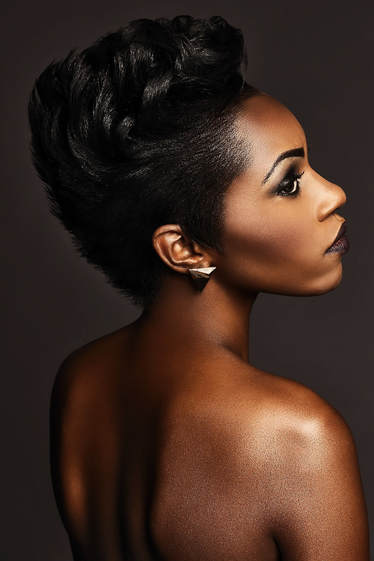 Black female model, modelling her hair. Her hair is cut short at the sides and all round and she has curly waves on the top.