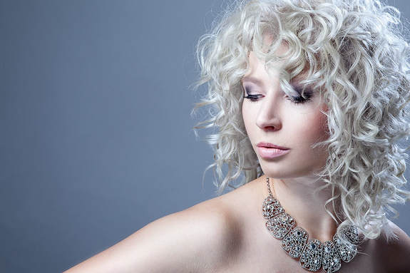 White model, modelling hair that  has been layered and is white and curly.