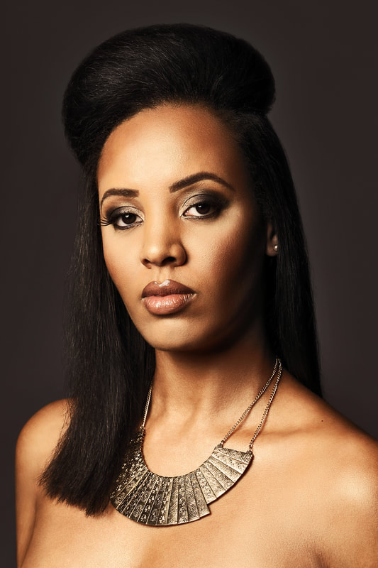 Black model, modelling hair. She has long straight hair going behind her back and the top is bunched into a big quif.