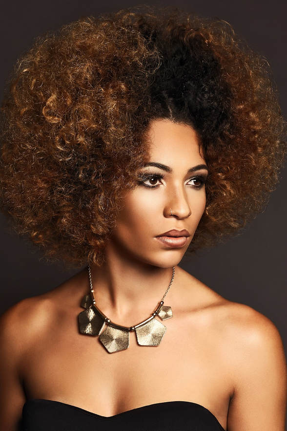 Black female model, modelling her hair. Her hair is soft, short and curly. The ends have been dyed brown and the middle is black.