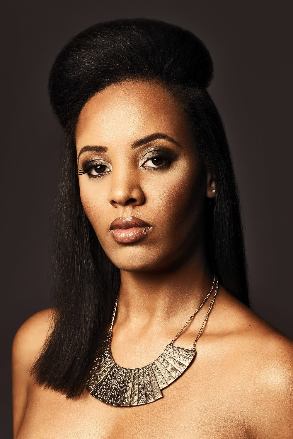 Black female model that is modelling her hair. She has shoulder lenthg hair that is straight and the sides and back are falling down whilst the front is styled up in a big quif.